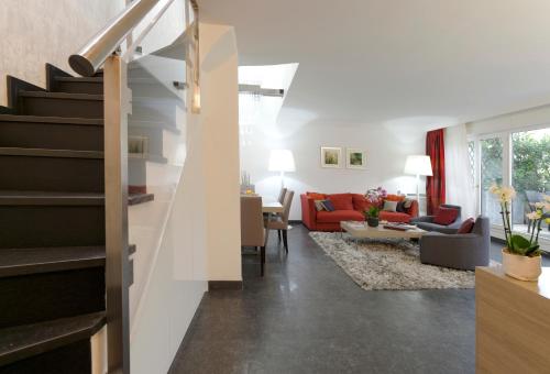 un salon avec un escalier et un canapé rouge dans l'établissement Résidence Alma Marceau, à Paris