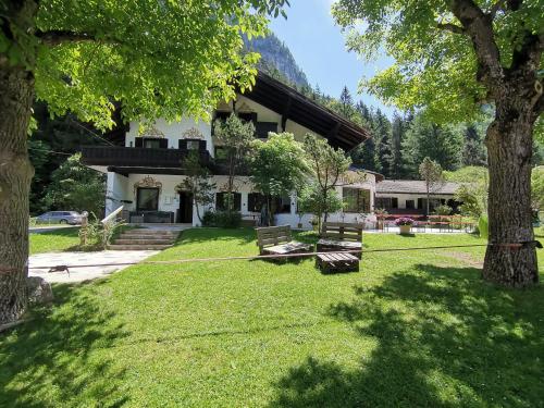 a house with a yard with benches and trees at Pension Almhof Baumgarten in Bad Reichenhall
