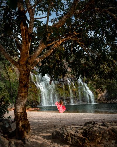 a woman sitting in front of a waterfall at Pousada Cachoeira Poço Encantado in Alto Paraíso de Goiás