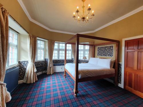 a bedroom with a bed and windows and a chandelier at The Glen Guesthouse in Selkirk