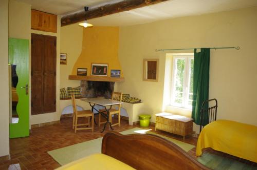 a living room with a bed and a table at Chambres d'Hotes La Grange au Negre in Alba La Romaine