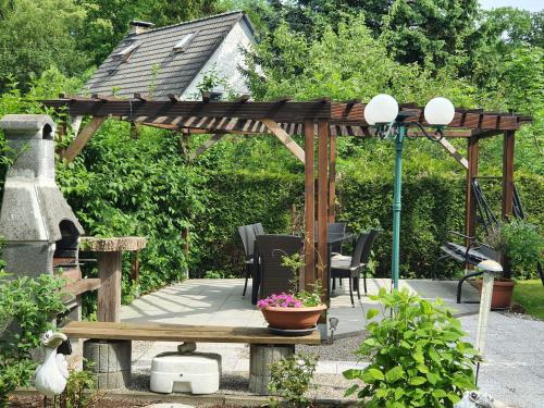 a wooden pergola with a table and chairs in a garden at Ferienwohnung Sonnenschein in Sagard