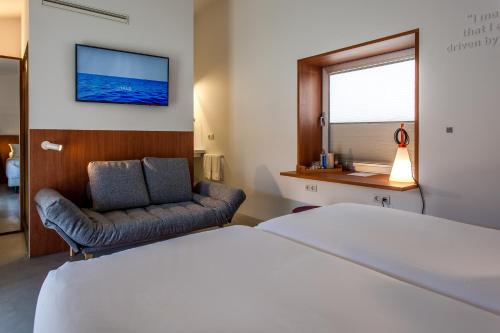 a hotel room with a bed and a chair at Hotel Bela Fisterra in Finisterre