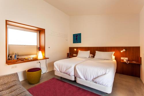 Un dormitorio con una gran cama blanca y una ventana. en Hotel Bela Fisterra, en Finisterre