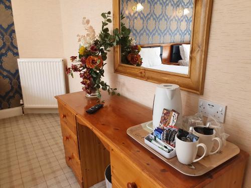 un mostrador con espejo y una mesa con tazas en The Glen Guesthouse en Selkirk