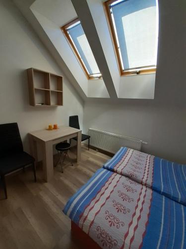 a bedroom with a bed and a desk and windows at Penzion Fontána in Mikulov