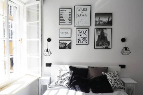 a bedroom with black and white pictures on the wall at Apartament Warsaw Old Town - Piwna Street in Warsaw