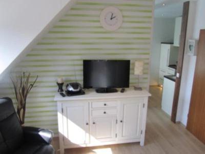 a living room with a tv on a white cabinet at Komfortappartement Robbe in Neuharlingersiel