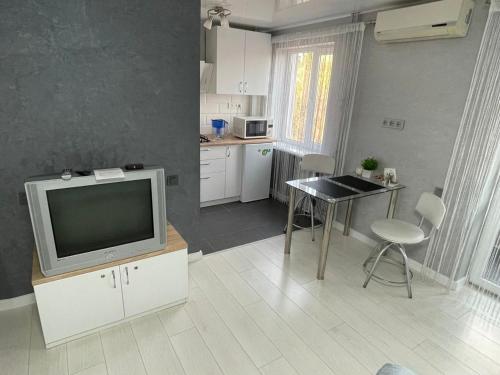 a living room with a television and a table with chairs at Апартаменты LUX в центре. Ярослава Мудрого 72 (97й квартал) in Kryvyi Rih