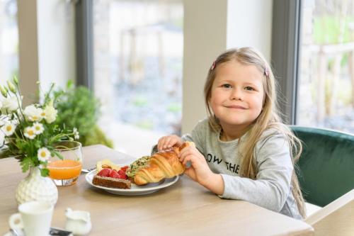 a little girl sitting at a table with a plate of food at HERBARIUM boutique hotel in Olomouc