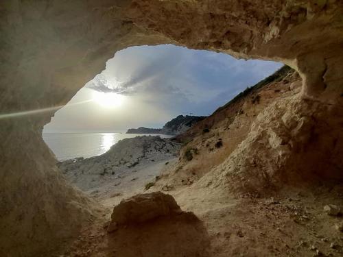 a cave on the beach with the sun in the background at Villa Adriana v rezidencii Toscamar in Jávea