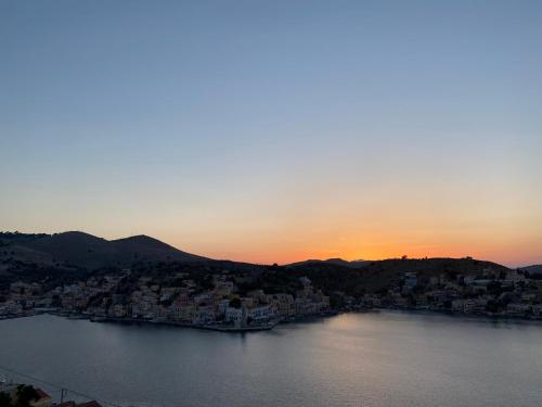 a large body of water with a city at sunset at Thodoris Infinity View Apartments in Symi