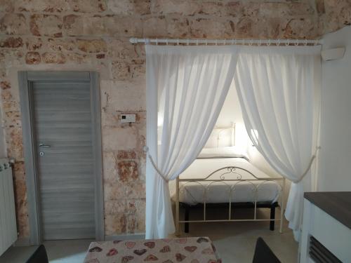 a bedroom with a bed with white curtains and a window at Soggiorno Galasso in Ostuni