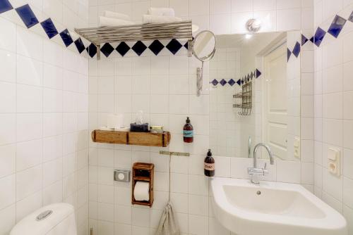 La salle de bains est pourvue de carrelage blanc, d'un lavabo et de toilettes. dans l'établissement Bongska Huset, à Abbekås
