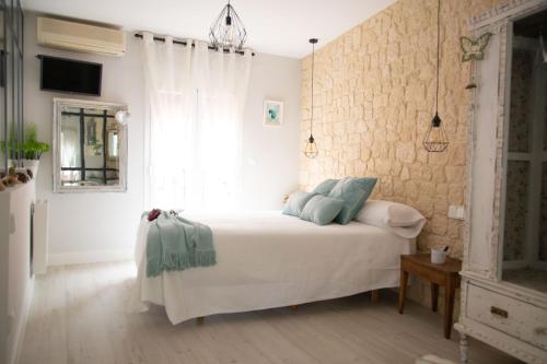 a bedroom with a white bed with blue pillows at Apartamentos Rincón de Cantarranas in Alhama de Aragón