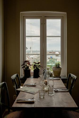 a long wooden table with glasses and a window at Bongska Huset in Abbekås