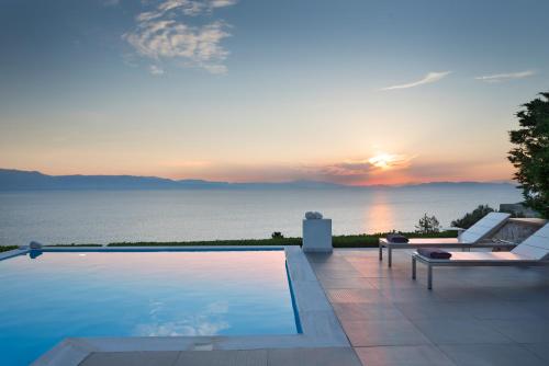 a pool with a view of the ocean at sunset at Villa Soligia Blue in Pefkali