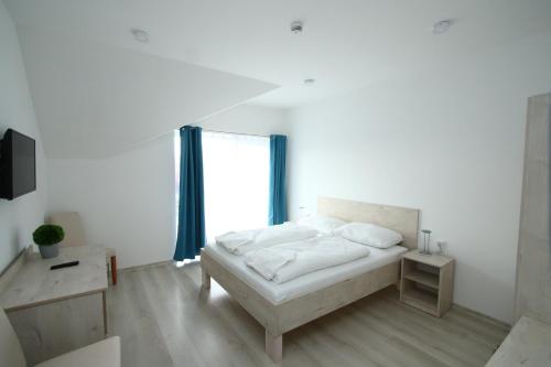 a white bedroom with a bed and a window at Hotel Aqua in Komárom