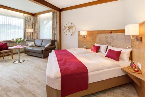 um quarto de hotel com uma cama grande e uma sala de estar em Gästehaus Gaiser em Baiersbronn