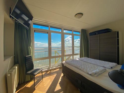 um quarto com uma cama e uma grande janela em Hello Zeeland - Appartement Port Scaldis 21-072 em Breskens