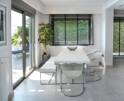 a dining room with a white table and chairs at Villa Soligia Blue in Pefkali