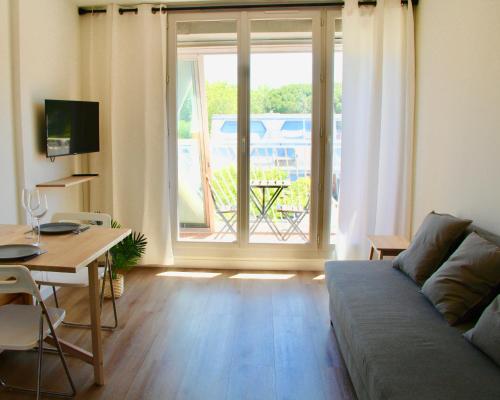 un salon avec un canapé et une table dans l'établissement LE SERINITY - Studio 10 min des plages à pieds, wifi, parking, clim, à La Grande Motte