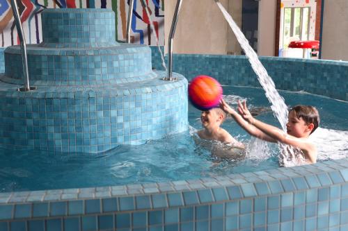 two children playing with a ball in a swimming pool at Danubius Hotel Bük in Bük