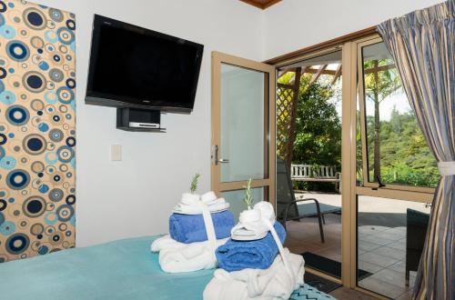 a room with a tv and towels on a bed at Chalet Romantica in Paihia