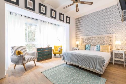 a bedroom with a bed and a chair and windows at Maison Reina in Valencia