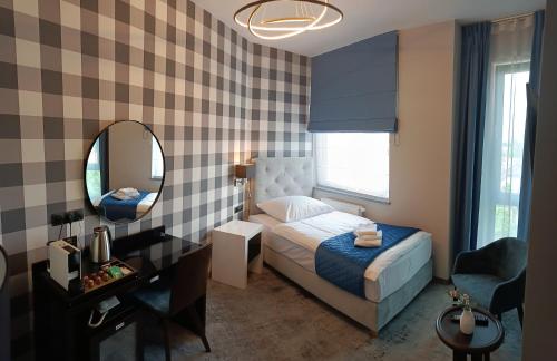 a bedroom with a bed and a mirror and a desk at Hotel Sanova in Jarosław