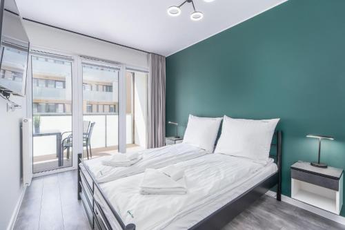 a bedroom with a large bed with a blue wall at Green Sea Apartamenty Kasprowicza in Kołobrzeg