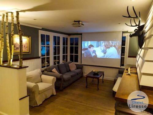 a living room with a couch and a large screen at Chalet la Liresse in Rochehaut