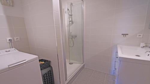 une salle de bain blanche avec une douche et un lavabo dans l'établissement Les Balcons Fleuris, à Sainte-Maxime