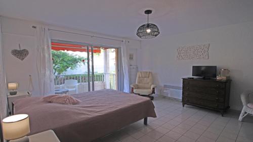 une chambre avec un lit et une télévision et un balcon dans l'établissement Les Balcons Fleuris, à Sainte-Maxime
