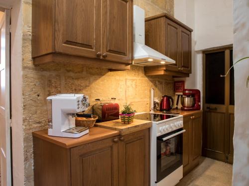 a kitchen with wooden cabinets and a white appliance at Tal-Karmnu Entire house with private heated pool and jacuzzi in Kirkop