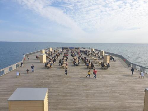 a group of people sitting on a pier near the ocean at Central Hastings, Stylish-Luxe, Seaside Apartment. in Hastings