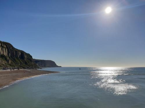 a beach with the sun shining on the water at Central Hastings, Stylish-Luxe, Seaside Apartment. in Hastings