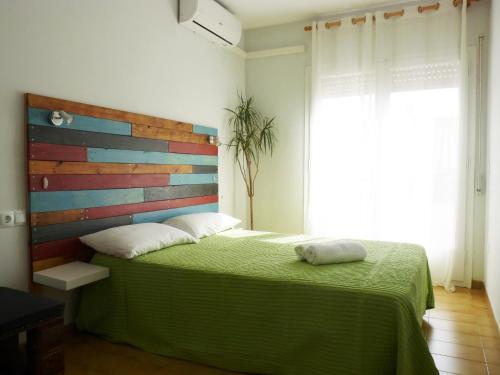 a bedroom with a green bed with a wooden headboard at Apartamento Dayok Costa Barcelona in Malgrat de Mar