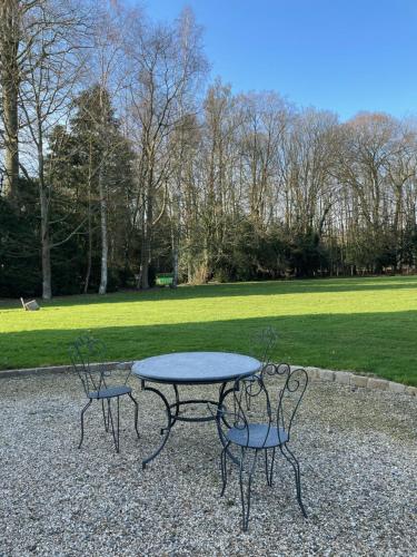 una mesa de picnic y dos sillas en un parque en Château de Trébons en Grainville-Ymauville