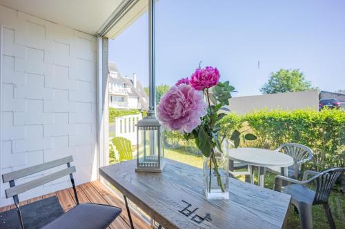 un vase de fleurs sur une table sur une terrasse dans l'établissement Sword, à Luc-sur-Mer