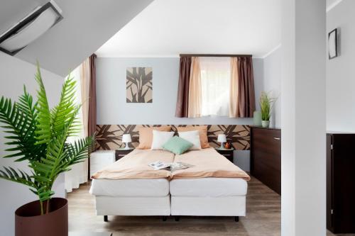 グダニスクにあるGuesthouse Balticの白いベッドと植物が備わるベッドルーム1室が備わります。