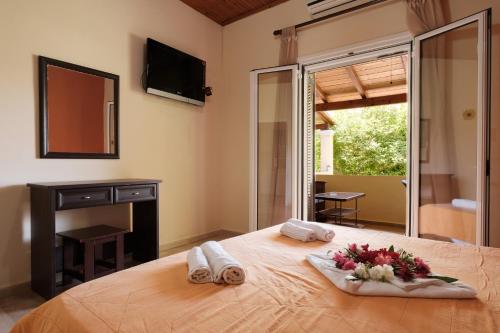 a bedroom with a bed with towels and flowers on it at Erifili Apartments in Sidari
