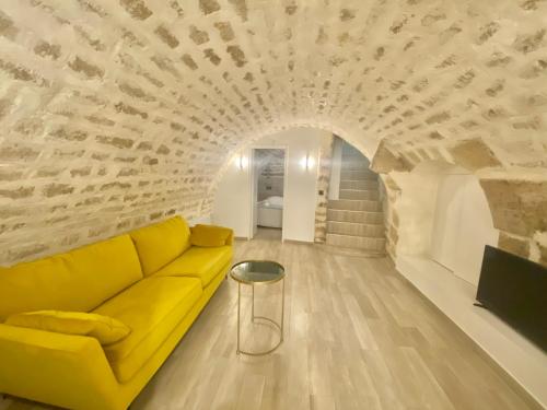 a yellow couch in a living room with a stone wall at Appartement République in Paris
