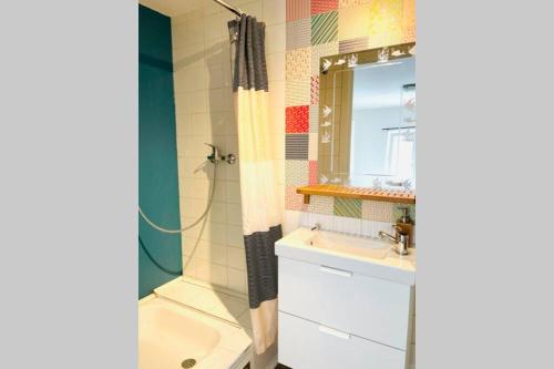 een badkamer met een wastafel en een douche met een spiegel bij Au coeur de la ville in Spa