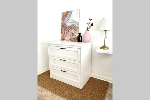 a white dresser with a lamp and a vase at Au coeur de la ville in Spa