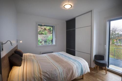 1 dormitorio con cama, ventana y silla en Appartement Tournette - Vue Lac, en Sévrier