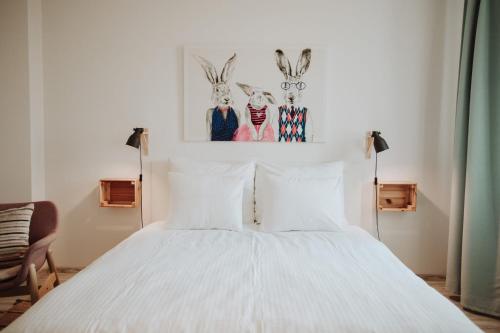 a bedroom with a white bed with two rabbits on the wall at Śpij w Paczkowie Apartments in Paczków