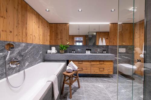 a bathroom with a tub and a sink at Brunnenhof Luxury Apartments in Lech am Arlberg