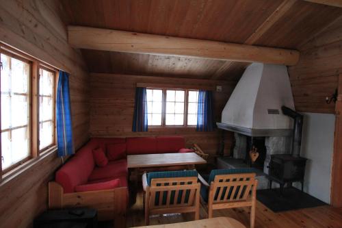 a living room with a red couch and a fireplace at Lusæter Timber Cabins in Heidal