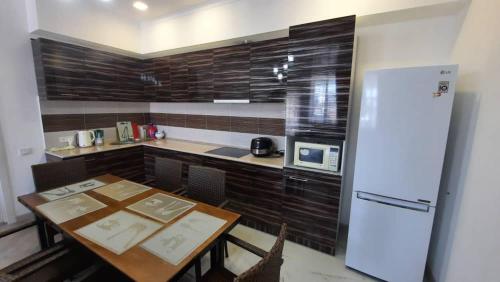 a kitchen with a table and a refrigerator at Уютный коттедж на берегу Иссык-Куля, Киргизия in Chok-Tal